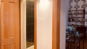A wooden door leading to a bathroom with a glass shower enclosure.