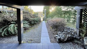 A covered pathway leading through a garden with ferns and a pile of rocks. - A Room With a View (Ucluelet)