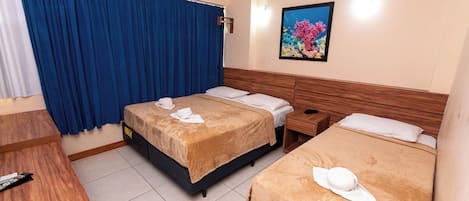 Una habitación de hotel con dos camas, un escritorio de madera, una mesita de noche y un cuadro de un arrecife de coral en la pared.