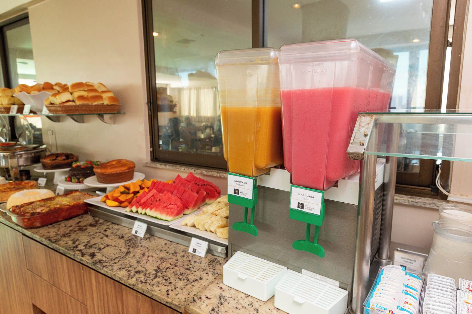A breakfast buffet with various food items and two fruit smoothies.