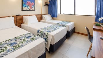 A hotel room with three beds, a desk, and a chair.