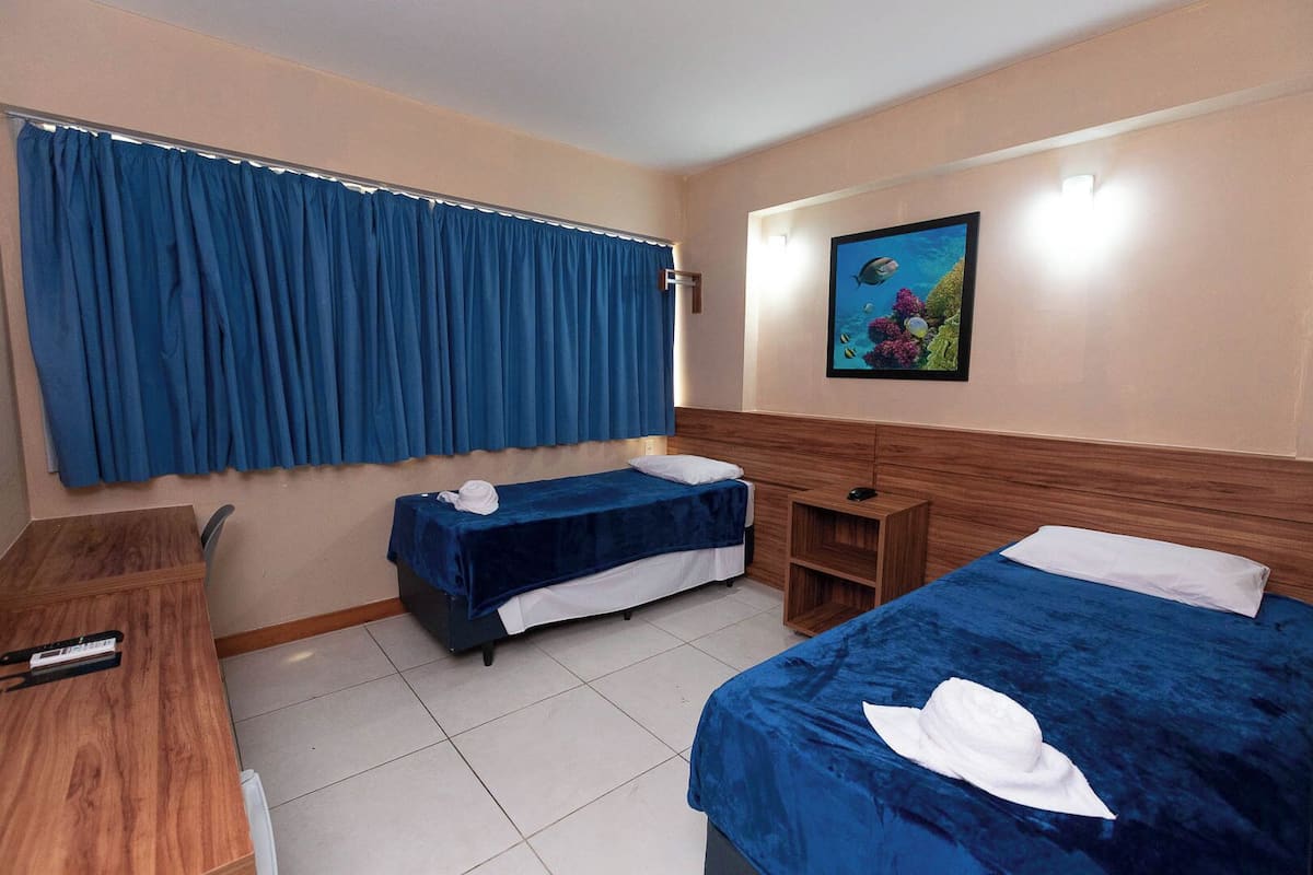 A hotel room with two beds, a desk, and a small table.