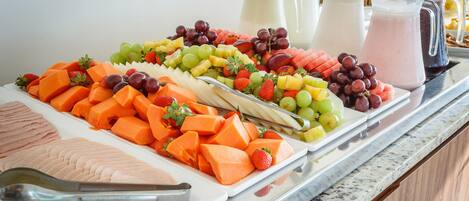 Un bufé con diversas frutas, verduras y una selección de bebidas.