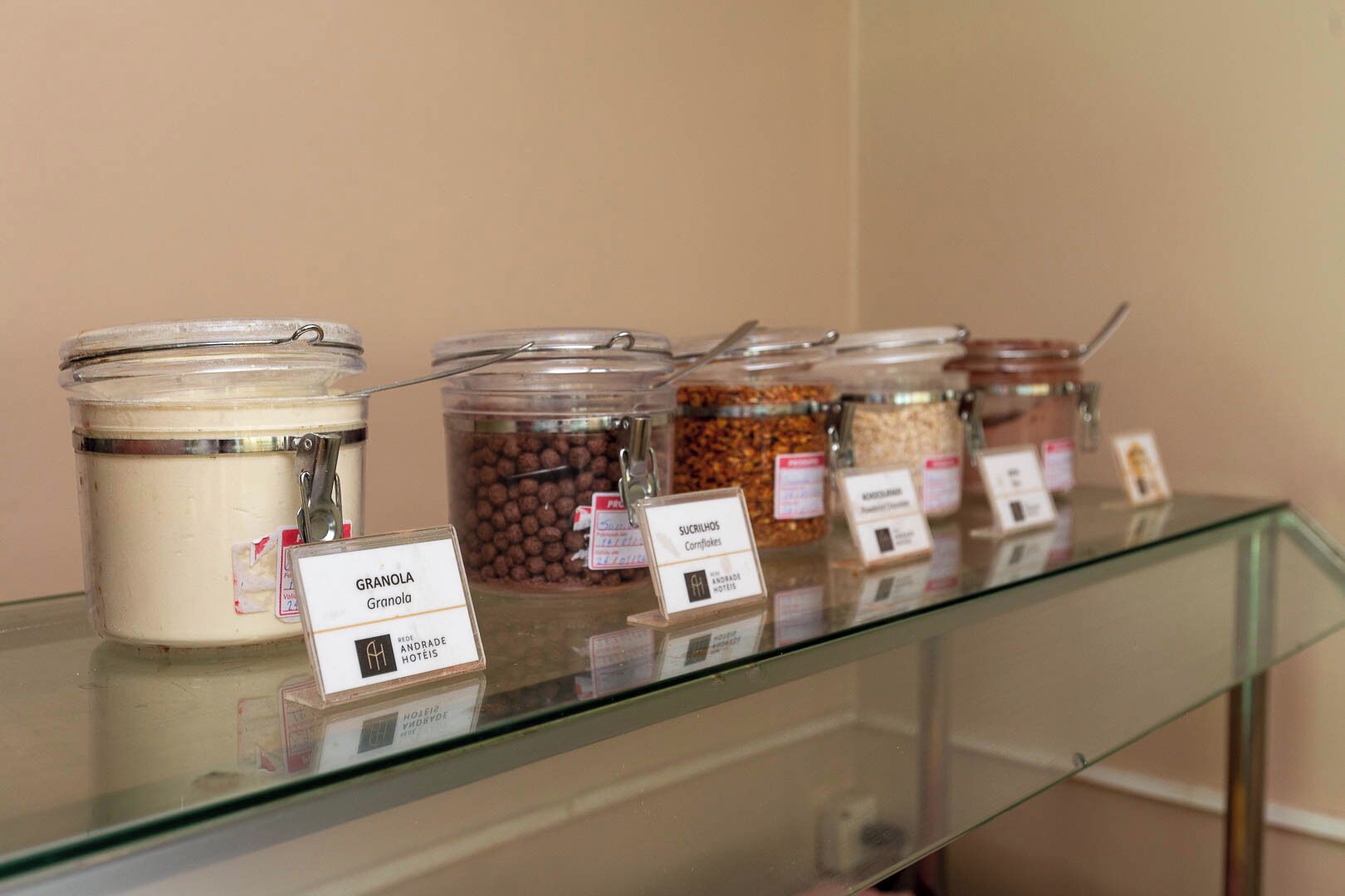 A glass display case with labeled jars of granola and other snacks.