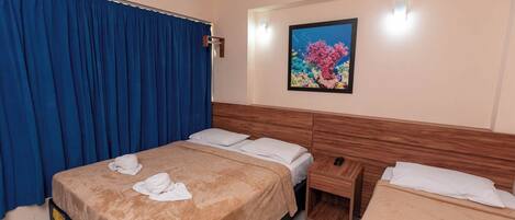 Une chambre d’hôtel avec un lit, une table de chevet, une tête de lit en bois, un rideau bleu et un tableau encadré au mur.