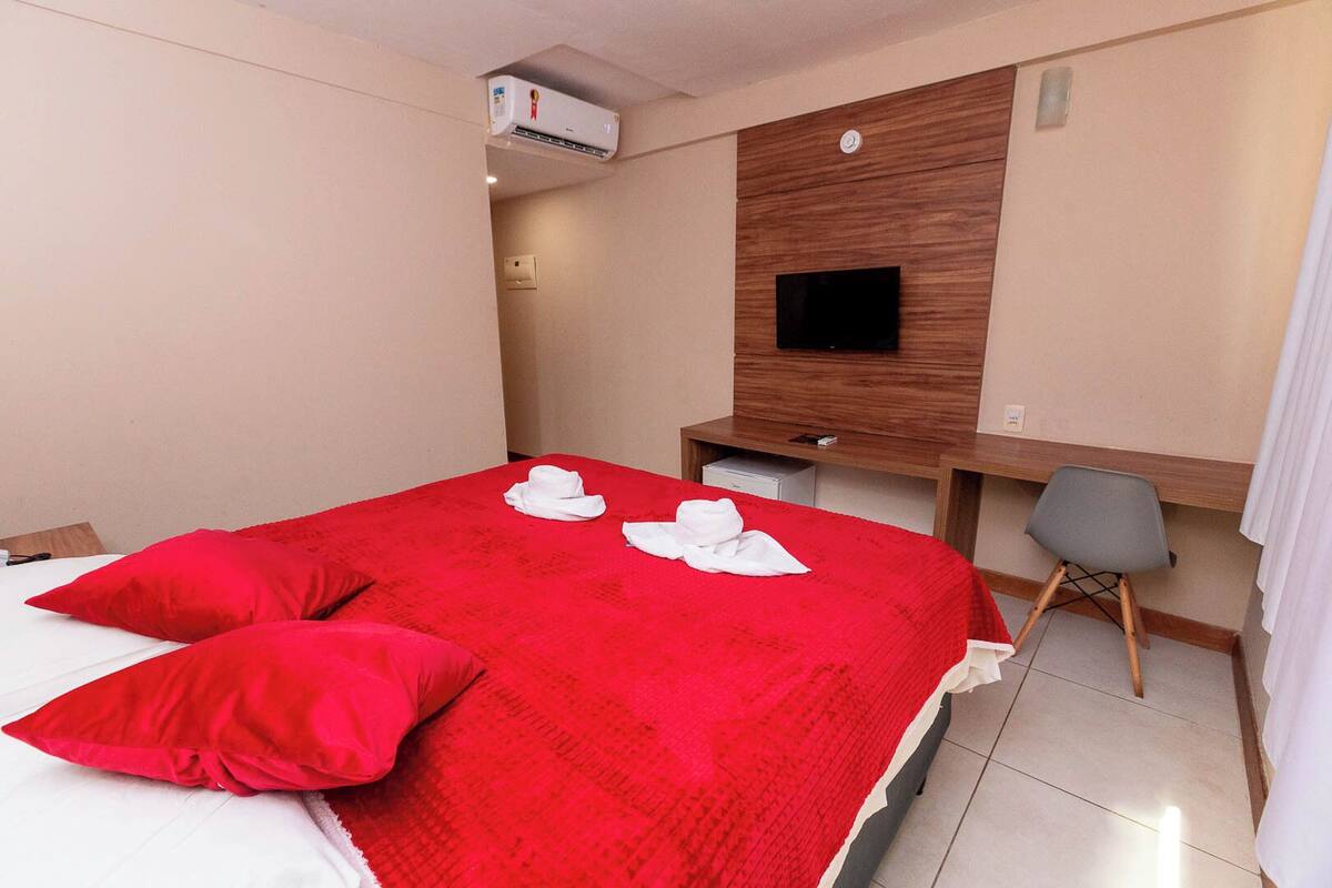 A hotel room with a bed, a desk, a chair, and a television.