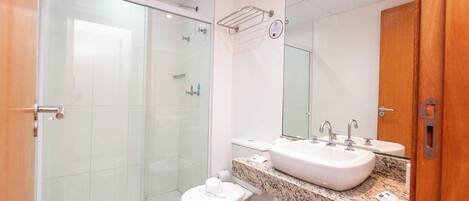 A modern bathroom with a glass-enclosed shower, a white toilet, and two sinks with faucets.