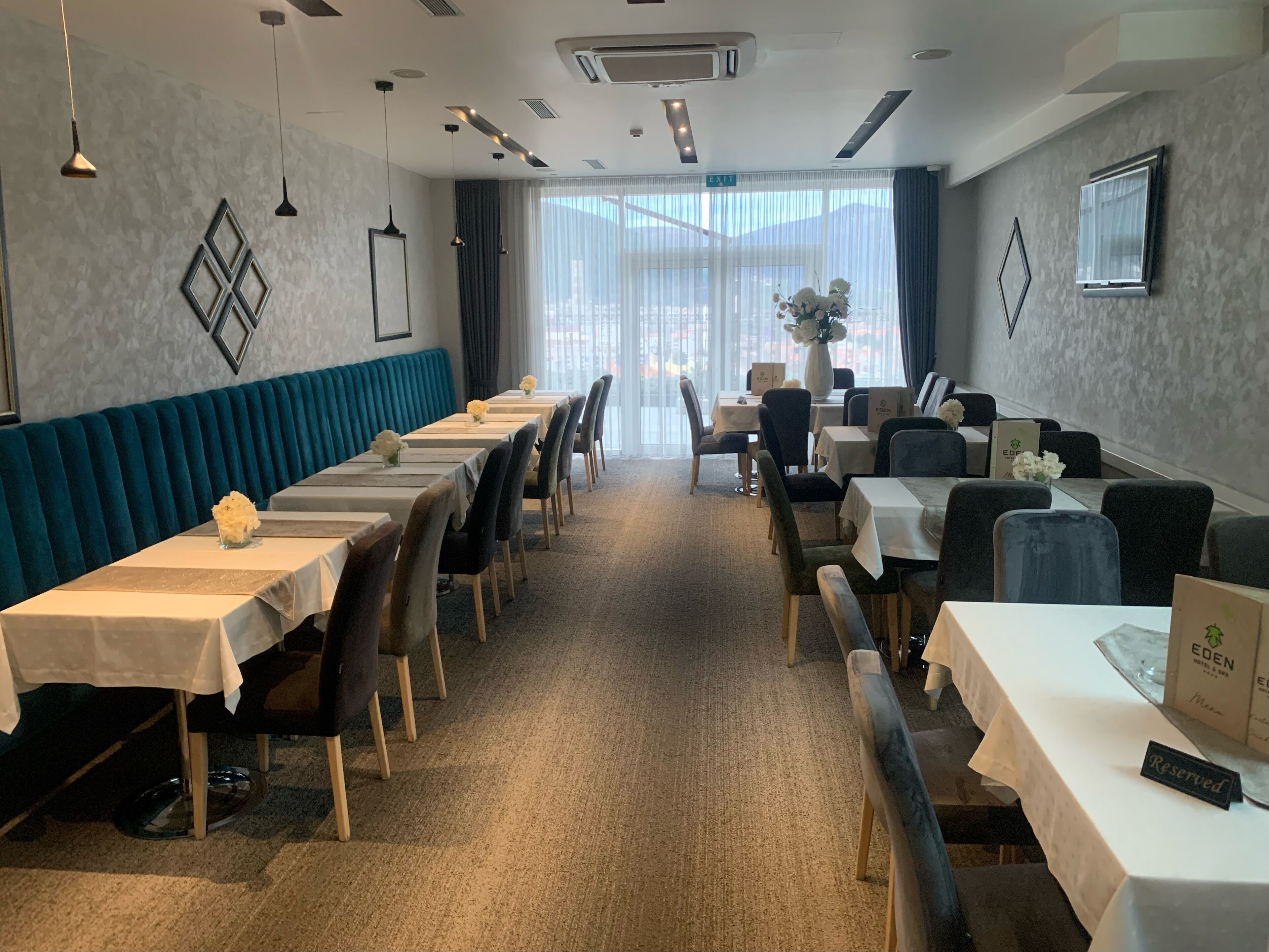 A hotel dining area with long tables, chairs, and a teal-colored bench.