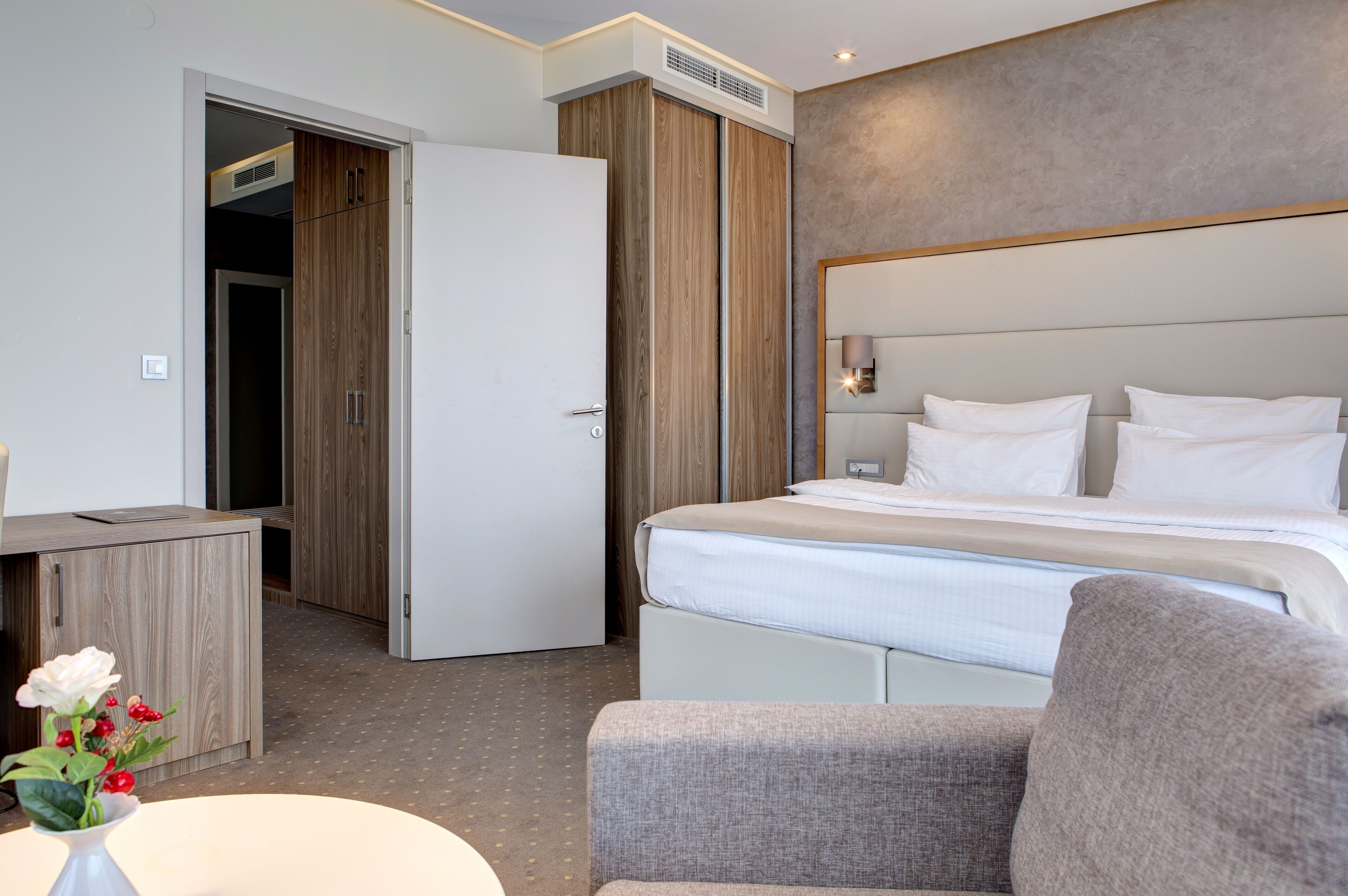 A hotel room with a bed, a desk, and a wardrobe.
