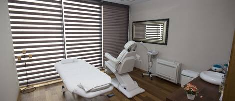 A clinical examination room with a treatment bed, examination table, and a sink.