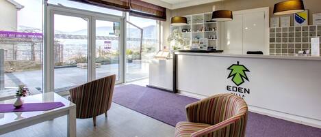 A reception area with a reception desk, chairs, a purple carpet, and a view of the outside.