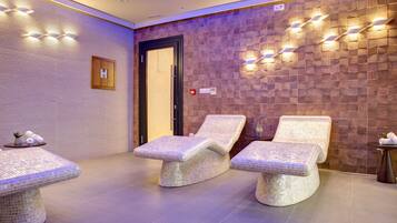 Um espaço de spa com três espreguiçadeiras revestidas em mosaico, parede de madeira com padrão herringbone e luminárias fixadas na parede.