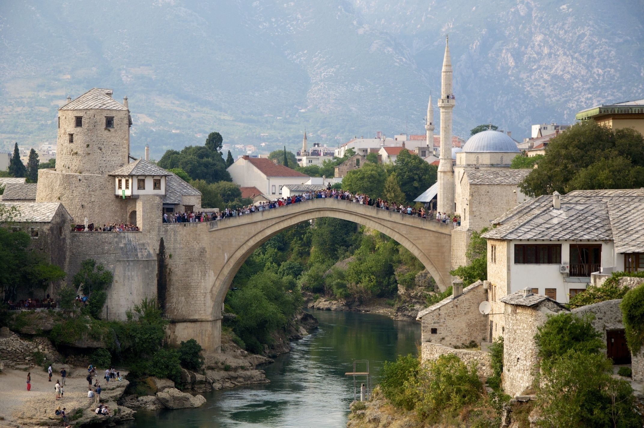 A stone bridge over a river with a crowd of people.