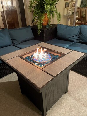 A modern living room with a sectional sofa, a glass-top coffee table with a fire feature, and a potted plant. - Location, location, location! Without bridges and locks in the Gulf of Mexico! (Cape Coral)