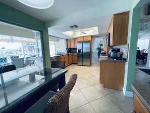 A modern kitchen with a dining area, large windows, and a ceiling fan. - Location, location, location! Without bridges and locks in the Gulf of Mexico! (Cape Coral)