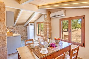 A dining area with a table set for four, a stone pillar, and a view of the outdoors.