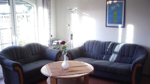 A living room with two grey sofas, a wooden coffee table, and a vase with a flower. - Vacation home in Dornumersiel 80-142b - 800-142b (Dornum)