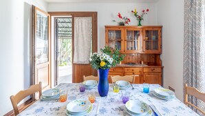 A dining area with a table set for four, a wooden cabinet, and a vase with flowers.