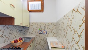 A kitchen with a gas stove, a sink, a window, and patterned tiles.