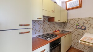 A kitchen with a gas stove, oven, and a window above the sink.