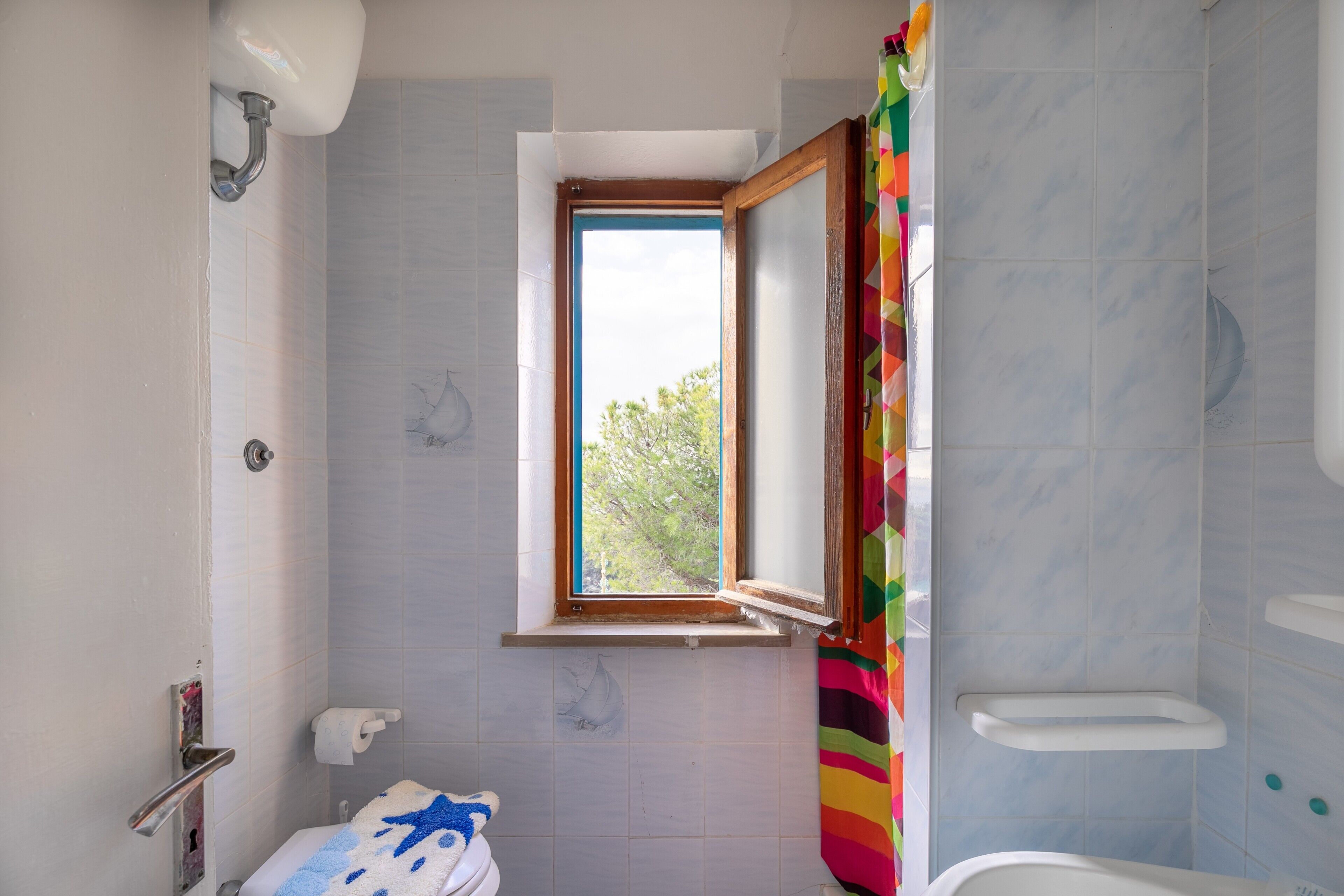 A bathroom with a window, a shower, and a toilet.
