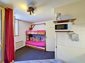 A compact room with a bunk bed, a microwave, and a small kitchenette. - Economical studio for 2 in Reberty 1850, near slopes (Les Menuires)