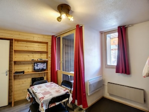 Cozy room with a single television, table, and chair, featuring a window with curtains.