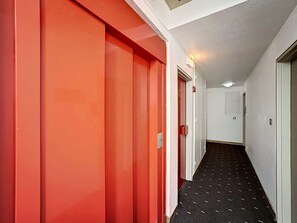 A hallway with red doors and a black patterned floor.