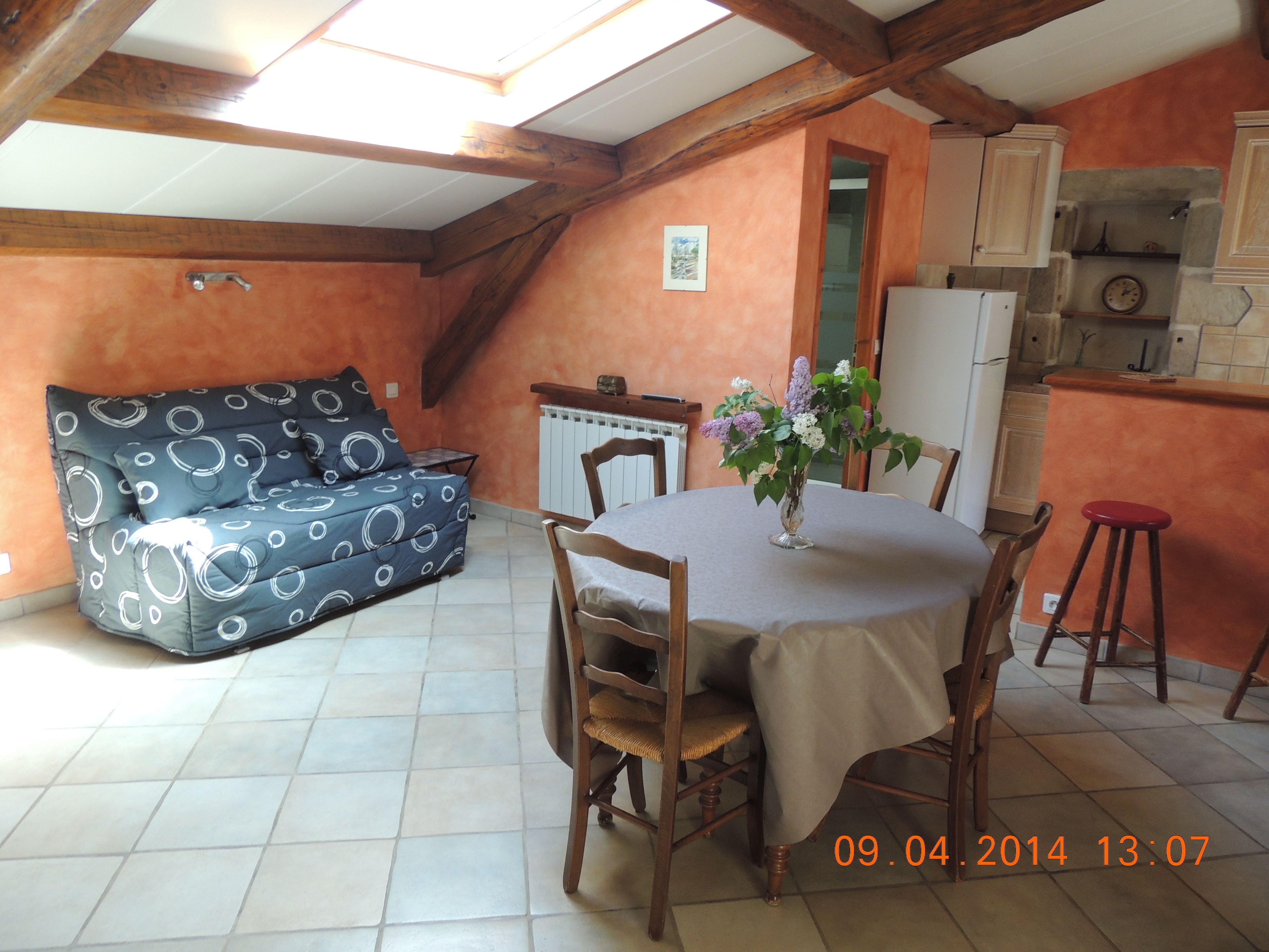 A dining area with a table, chairs, a sofa, and a flower vase.