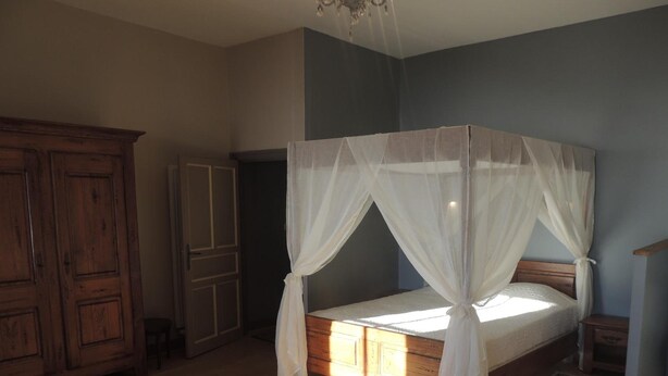 Un dormitorio con cama con dosel, armario de madera y un espejo grande.