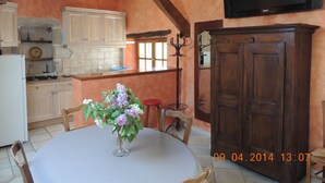 Una cocina con armarios de madera, estufa y mesa de comedor con sillas.