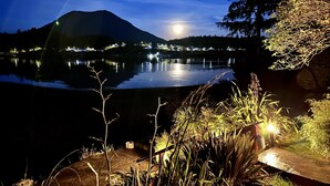 A nighttime view of a lake with a mountain in the background, illuminated by artificial lights. - Sea Esta (Ucluelet)