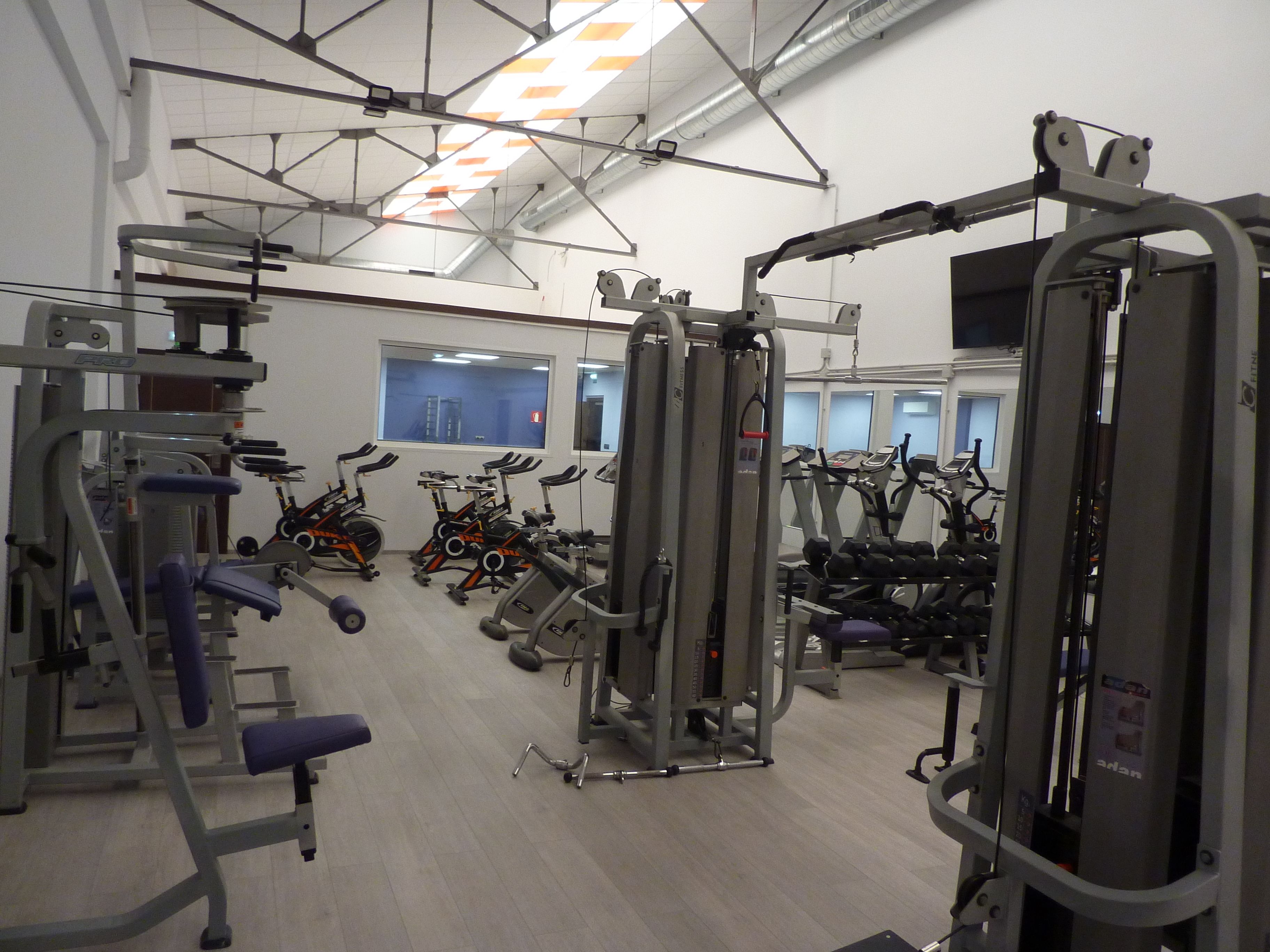 Un gimnasio con diverso equipo de ejercicio, que incluye cintas de correr, bicicletas estáticas y máquinas de pesas.