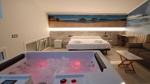 Una habitación con una bañera grande, dos camas, un sofá y un mural con una escena de playa.