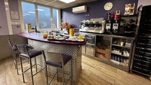 Una barra de desayuno con asientos, una máquina de café y un reloj en la pared.