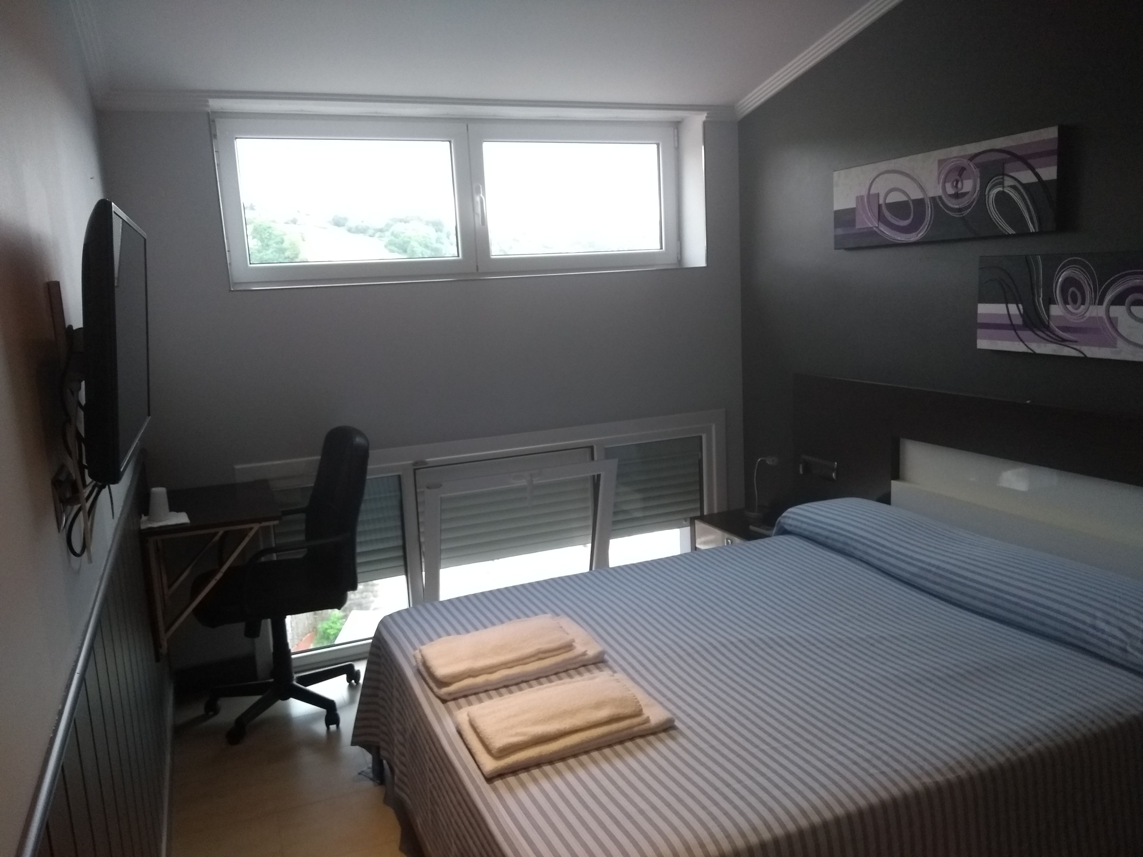 Une chambre à coucher avec un lit, un bureau, une chaise et une fenêtre.