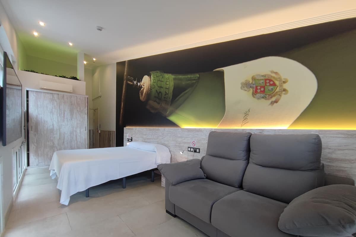 A modern hotel room with a bed, a sofa, and a large wall mural.