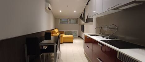 Una cocina compacta con comedor, sofá y televisor.