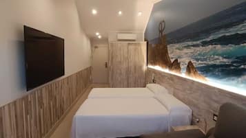 A hotel room with a large bed, a flat-screen TV mounted on the wall, and a mural of a seascape.