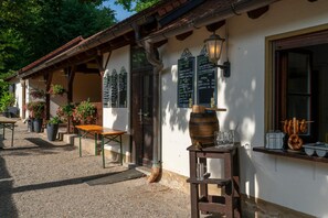 A rustic outdoor seating area with a wooden table and chairs, a barrel, and a chalkboard menu. - Mörsbergei Landgasthof (Bubenreuth)