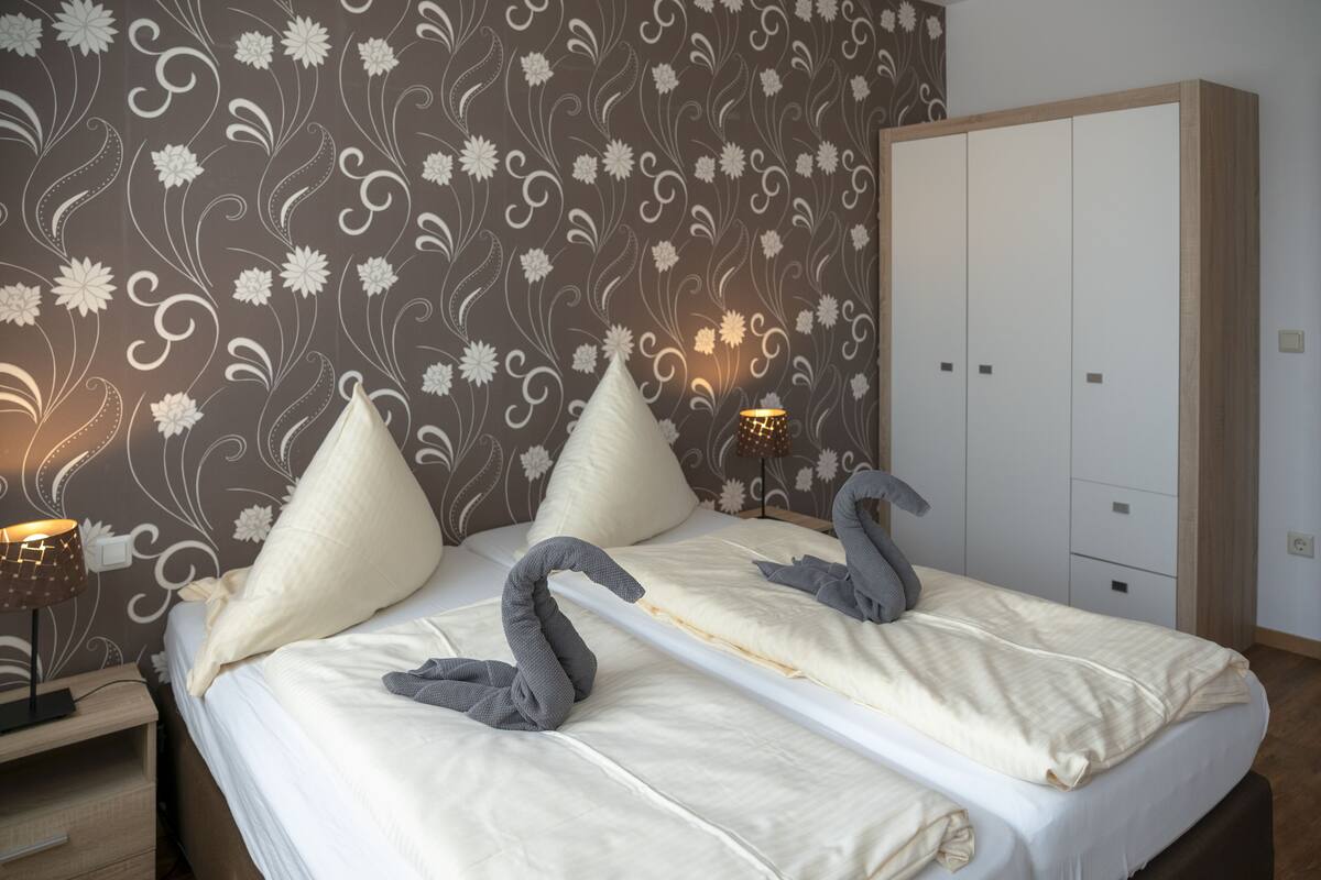 A neatly made bed with decorative pillows, a bedside lamp, and a wardrobe in a hotel room.