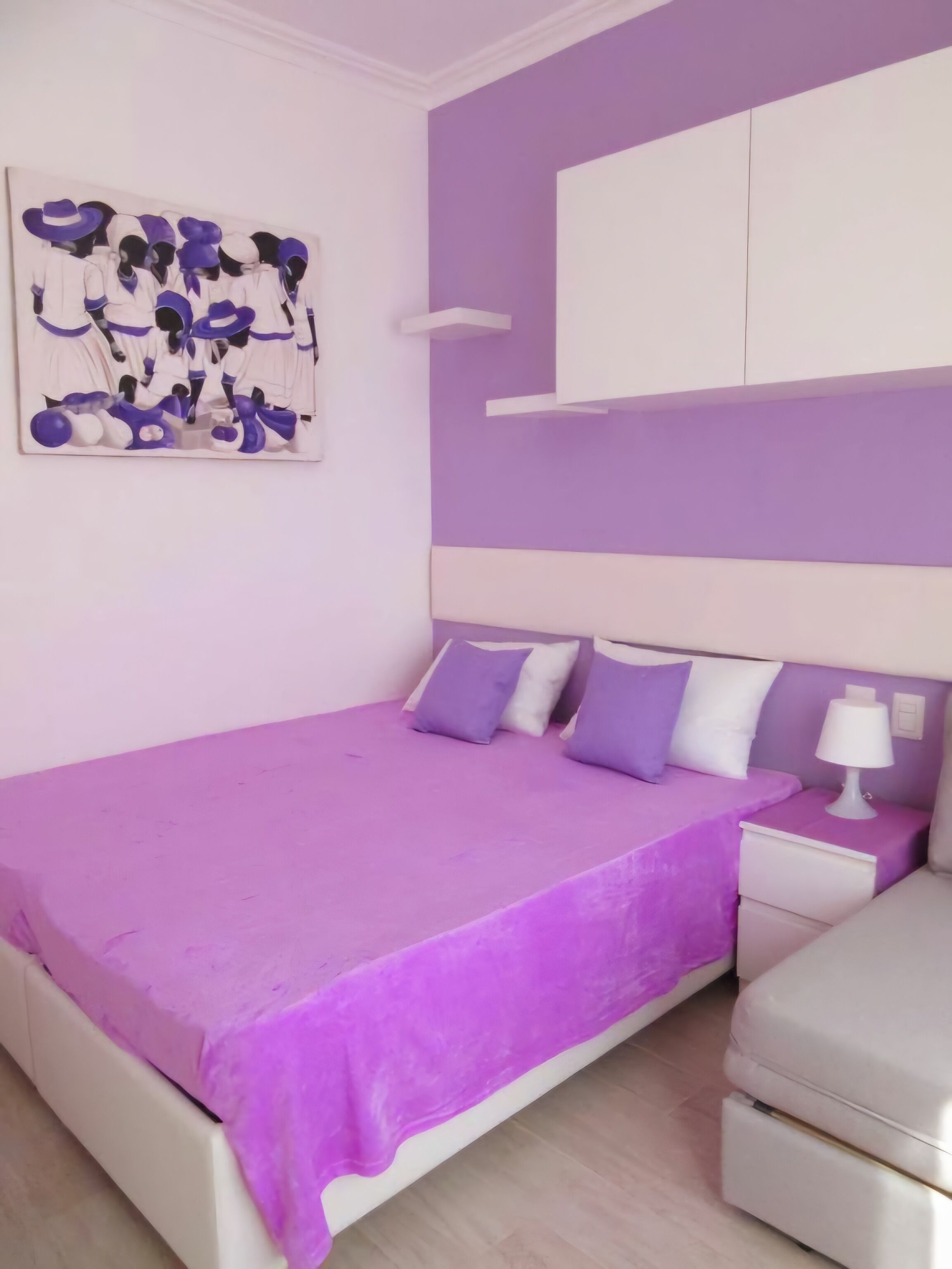 Une chambre à coucher avec un grand lit, une table de chevet, une commode et une œuvre d’art accrochée au mur.