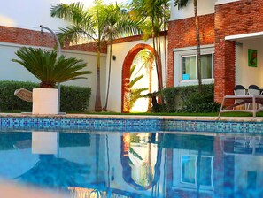 Una piscina al aire libre, sillones reclinables de piscina