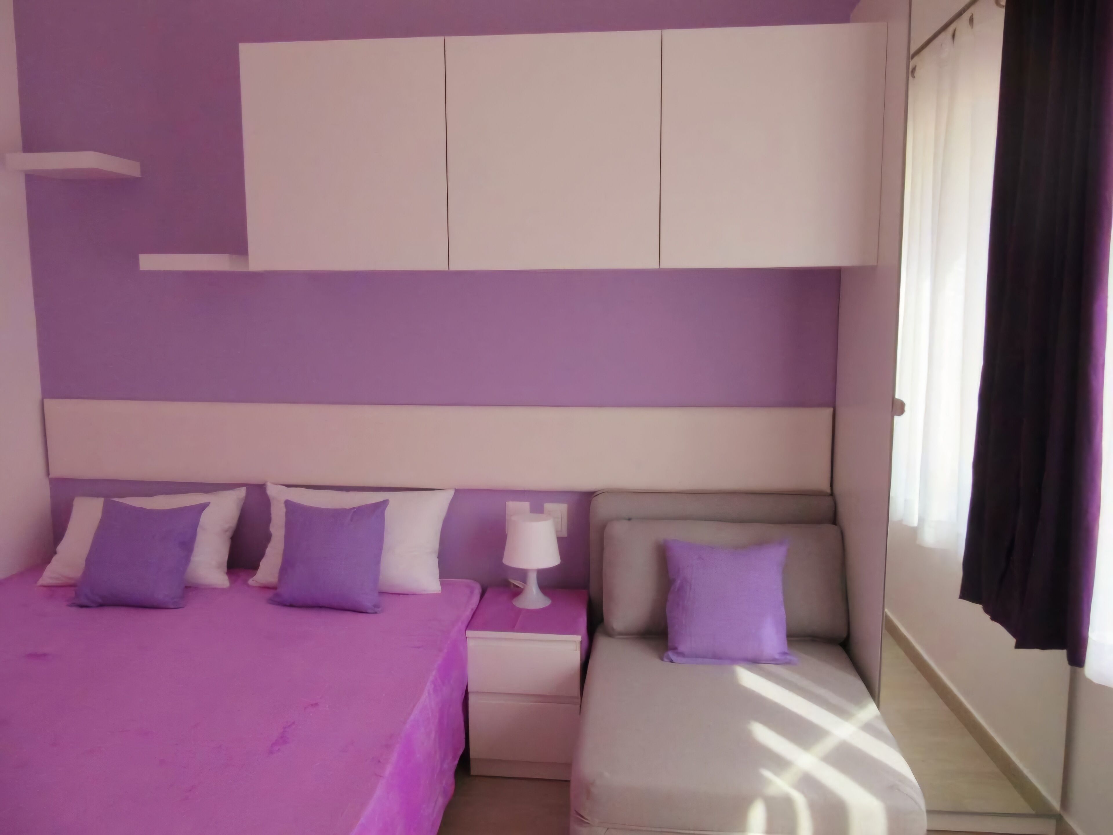 Una camera da letto con un letto, un comodino, una cassettiera e una finestra con tende.