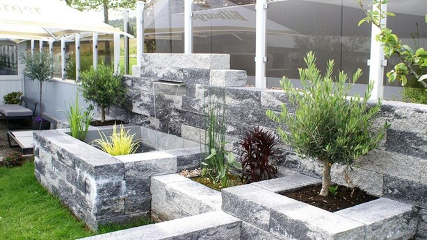 A landscaped garden with stone planters and various shrubs. - Hotel Restaurant Haus Schieferstein (Dahlem)