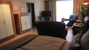 A hotel room with a sofa, a TV, a desk, and a plant. - Hotel Restaurant Haus Schieferstein (Dahlem)