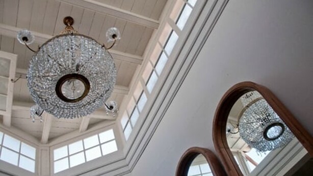 A grand chandelier in a high-ceilinged room with large windows and a mirror reflecting the chandelier. - Quinta Miraflores Boutique Hotel (Lima)