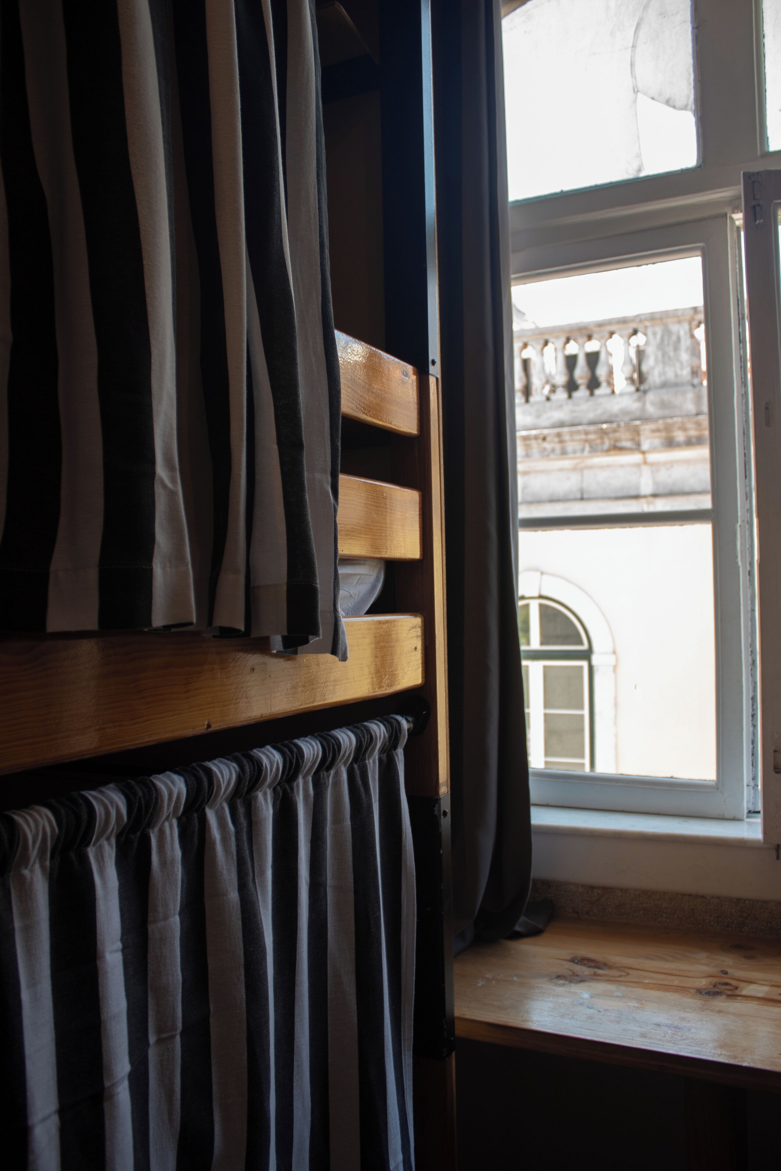 A room with a wooden bench and a window with curtains.