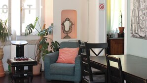 Una sala de estar con un sofá, sillas, una mesa y un ventanal con cortinas.
