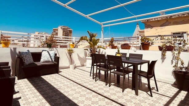 A rooftop terrace with a dining table and chairs, a sofa, and potted plants. - Domus Claudia - Holiday Homes (Siracusa)